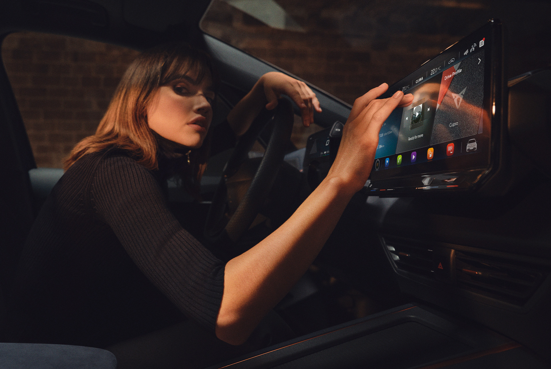 Mujer dentro de un CUPRA Born utilizando el salpicadero y la pantalla de Infotainment