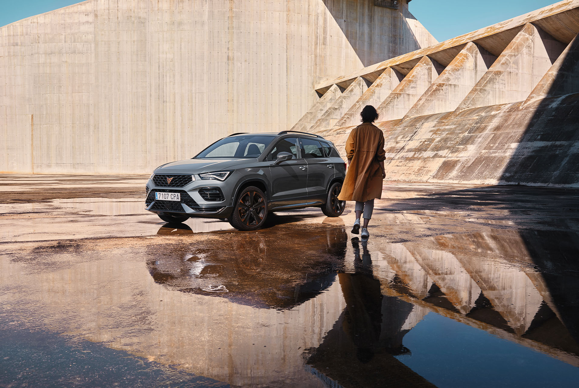 Una persona caminando hacia un CUPRA Ateca, se ven las líneas atrevidas y deportivas del coche y su forma dinámica, que representa el espíritu de la tribu CUPRA.