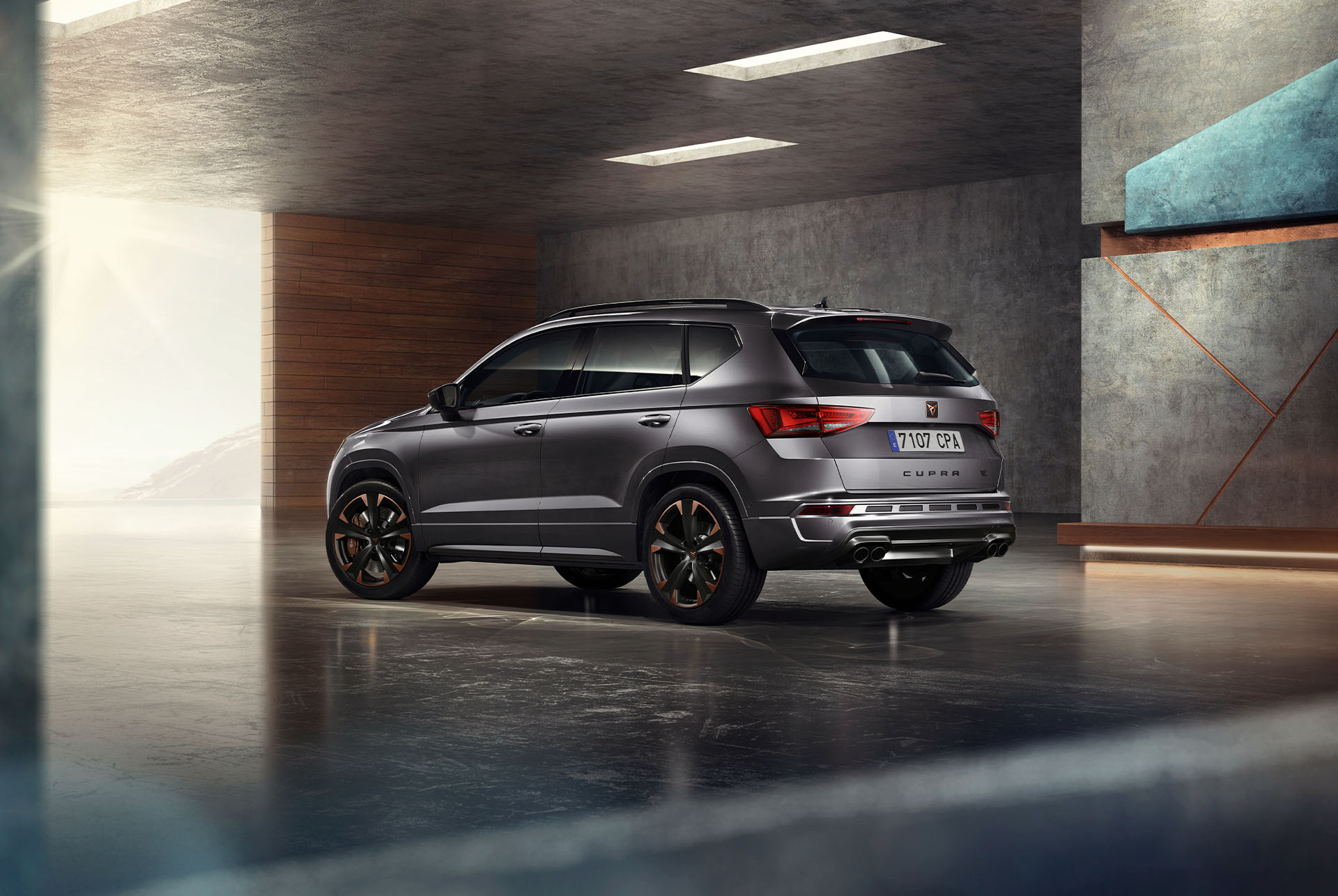 Un CUPRA Ateca SUV gris sobre fondo blanco. El coche presenta una atrevida parrilla delantera, faros LED y llantas de aleación con detalles en cobre, que resaltan su diseño de coche deportivo.