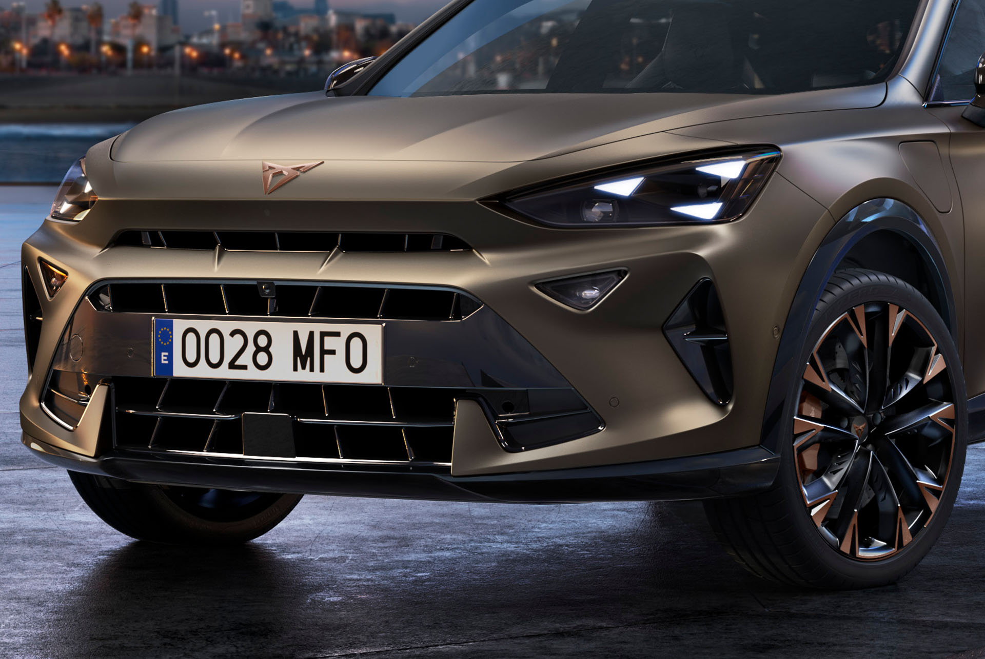 Primer plano de la parte delantera de un CUV CUPRA Formentor 2024 de color Century Bronze, con llantas de acabado en Copper, los característicos faros delanteros con forma de ojo triangular y el distintivo logotipo CUPRA.