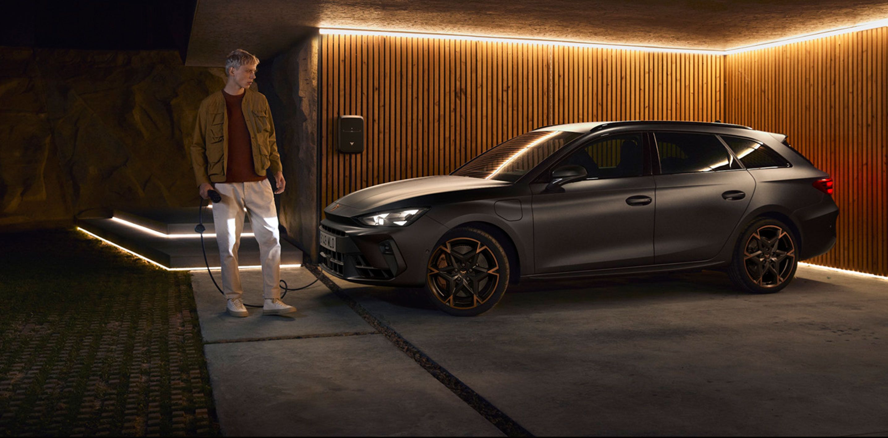 electric and hybrid car home charging in garage with wall charger installed, owner holding cable